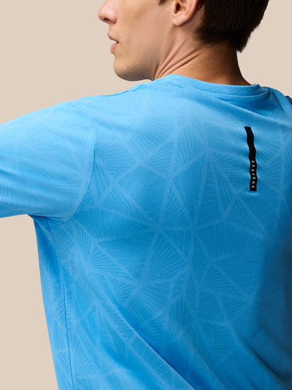 Back view of Flow Training Engineered Knit T Shirt in cool blue with geometric knit pattern and branded back neck tape