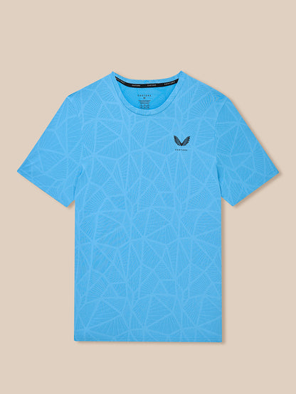 Flat lay of blue Flow Training Engineered Knit T Shirt with allover geometric pattern and Castore logo on left chest
