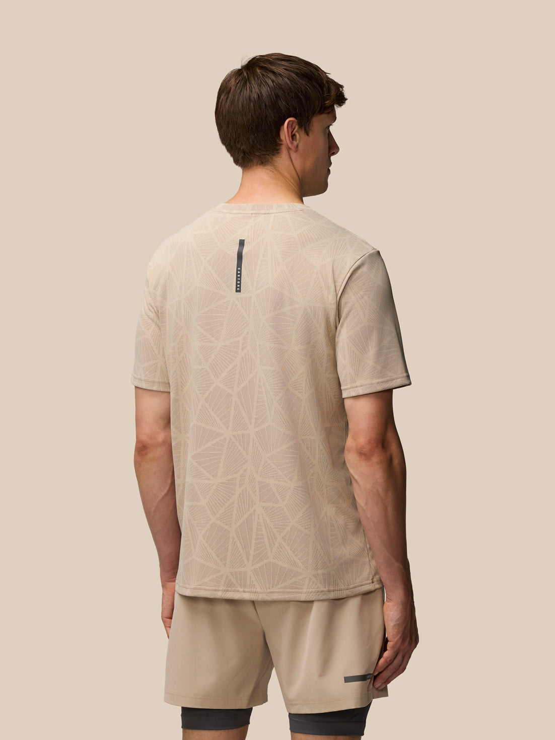 Back view of Flow Training Engineered Knit T Shirt with branded neck tape and beige geometric knit