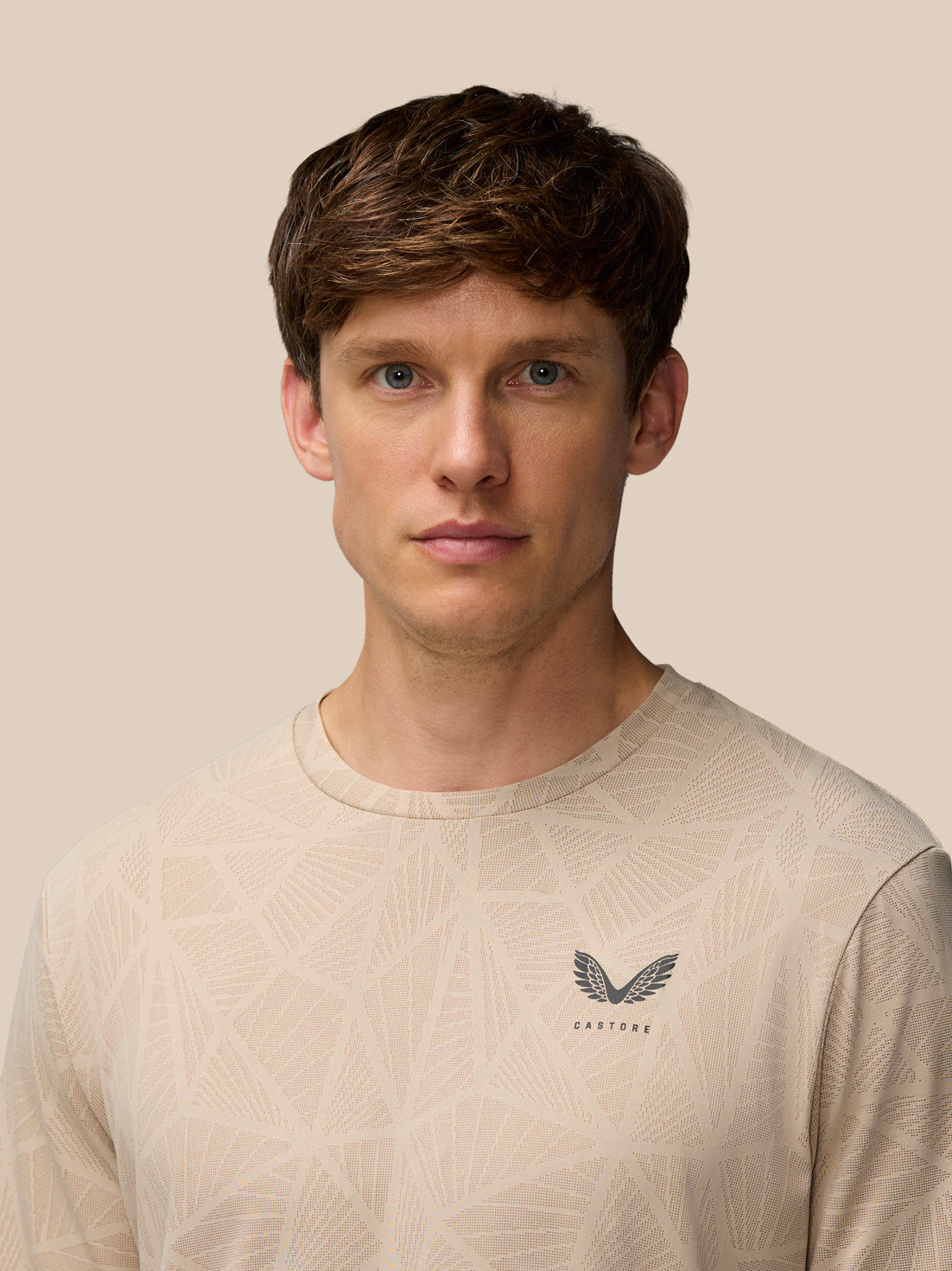 Front view of a man wearing mushroom Flow Engineered Knit T Shirt with geometric knit pattern and Castore logo on left chest