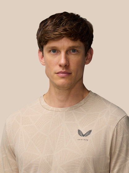 Front view of a man wearing mushroom Flow Engineered Knit T Shirt with geometric knit pattern and Castore logo on left chest