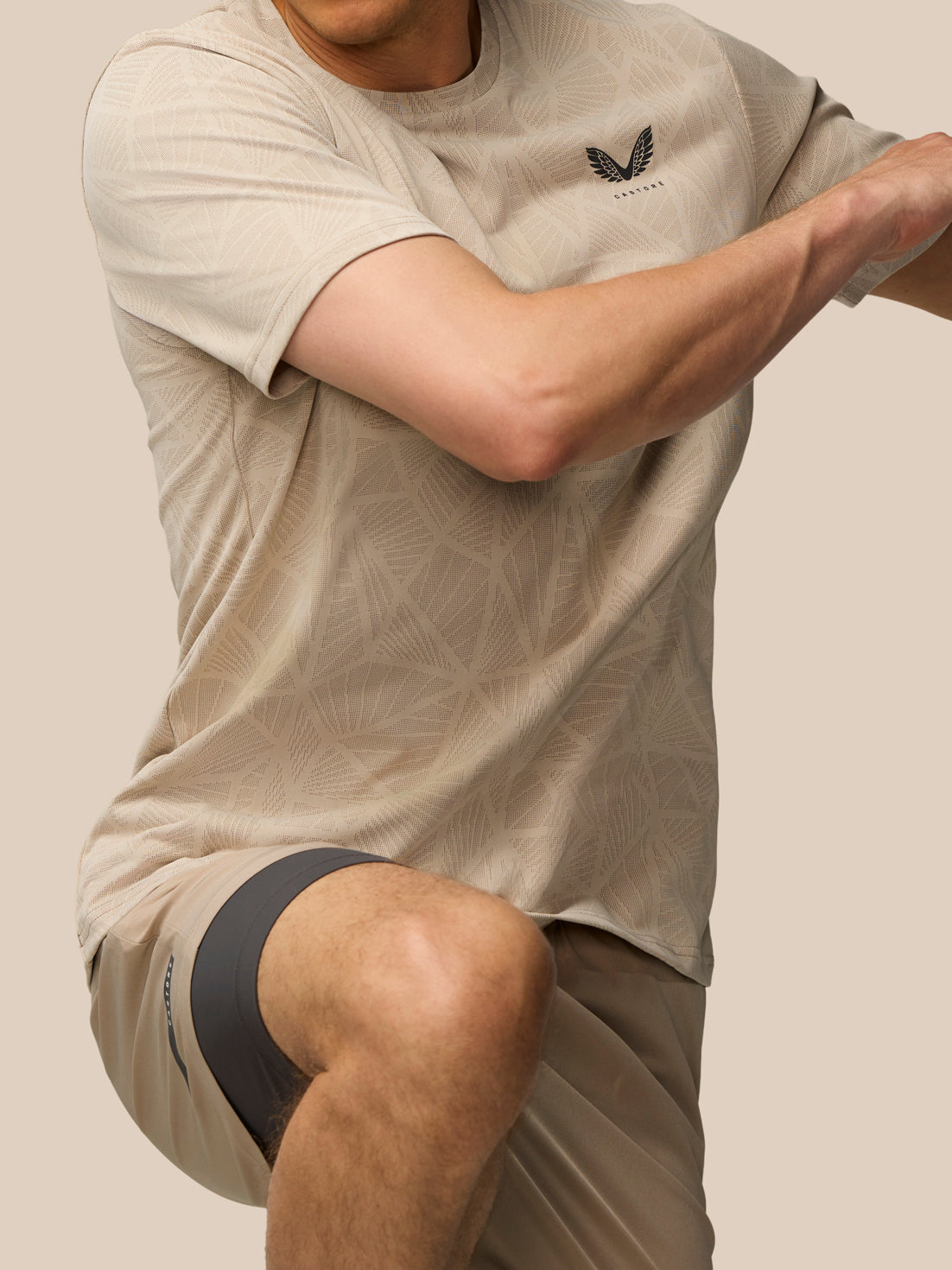 Side view of a man wearing mushroom Flow Engineered Knit T Shirt with geometric knit pattern and Castore logo on left chest