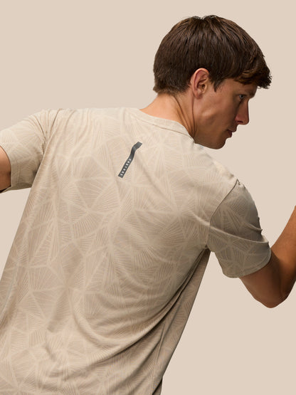 Back view of a man wearing Flow Engineered Knit T Shirt in mushroom with a geometric knit pattern and a vertical Castore label on the upper back