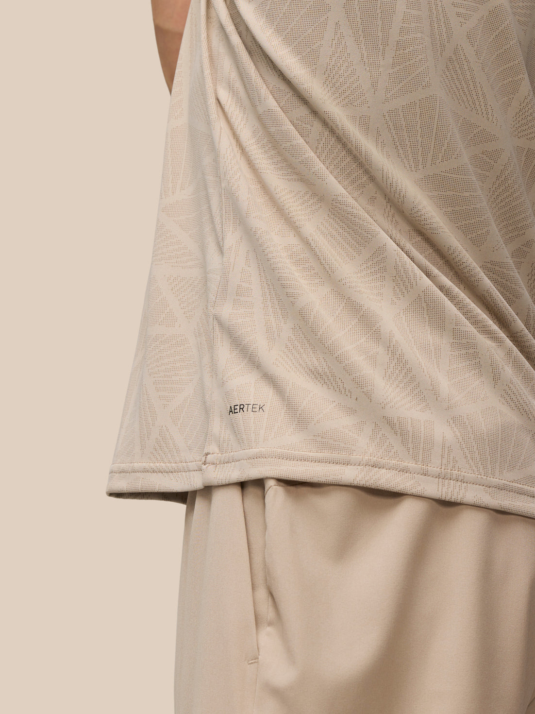 Beige mushroom Flow Engineered knit fabric with a geometric pattern and AerTek branding along the hem