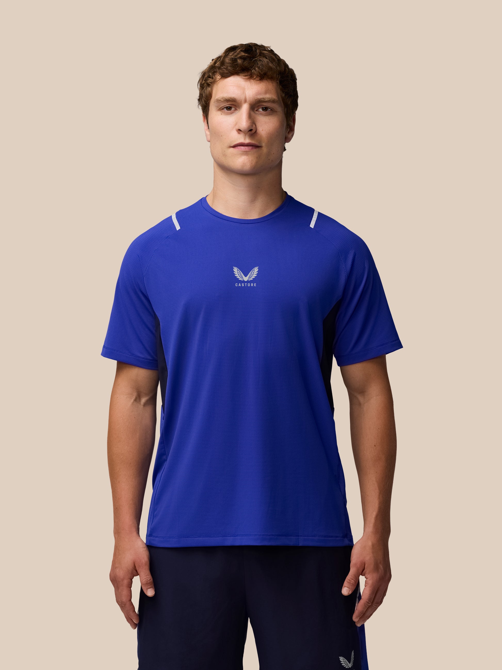 Three quarter view of male model in Azure Blue Apex Training T Shirt showing chest logo and white shoulder accents