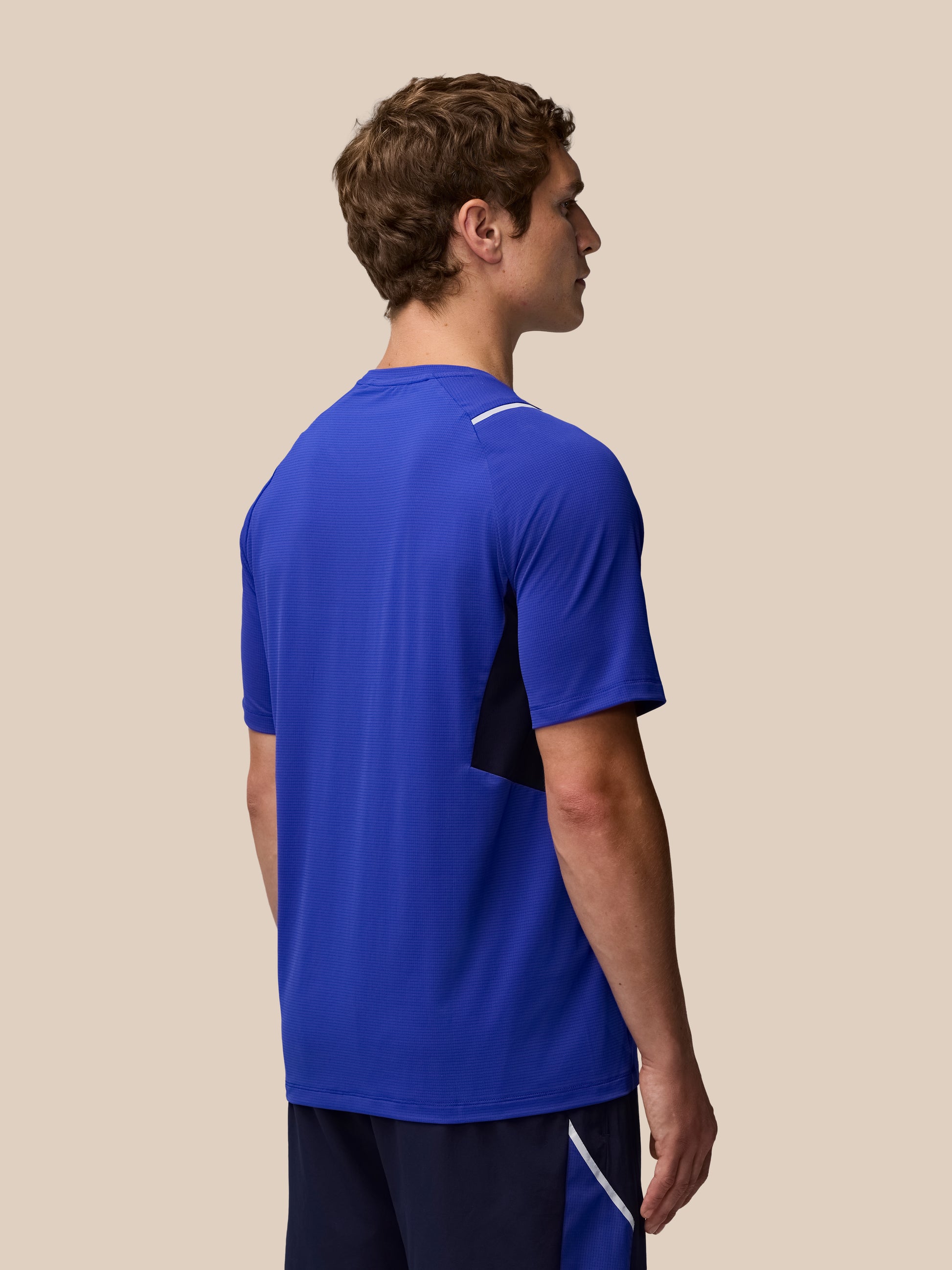 Profile view of male model in Azure Blue Apex Training T Shirt with reflective shoulder details and color block side panel