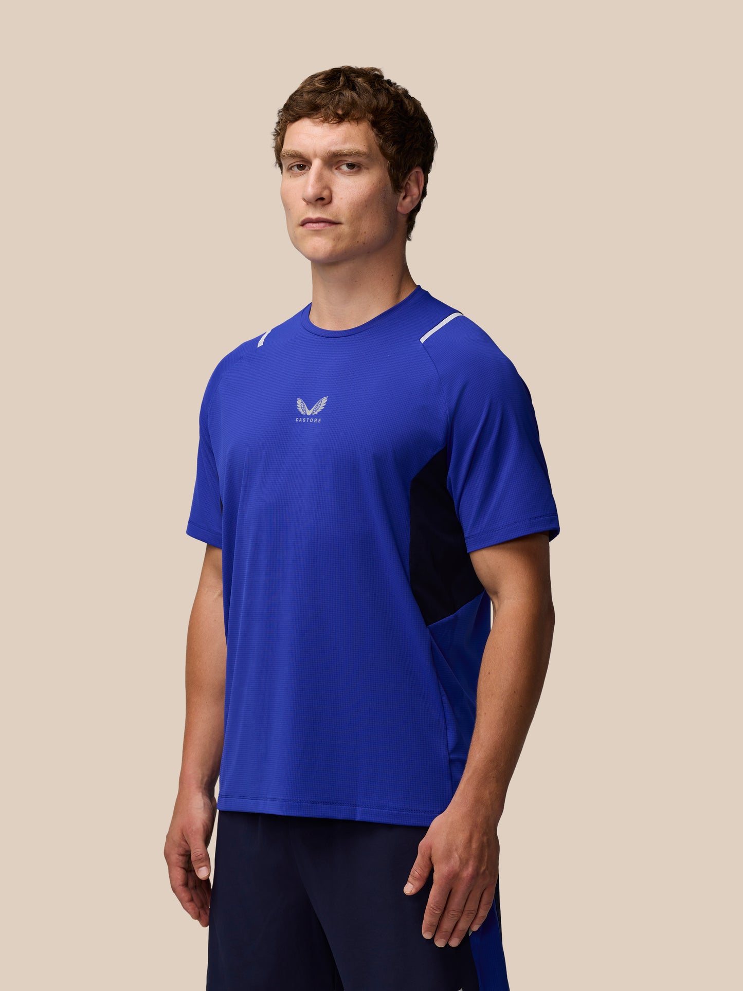 Male model wearing Azure Blue Apex Training T Shirt with Castore logo on chest and reflective shoulder details