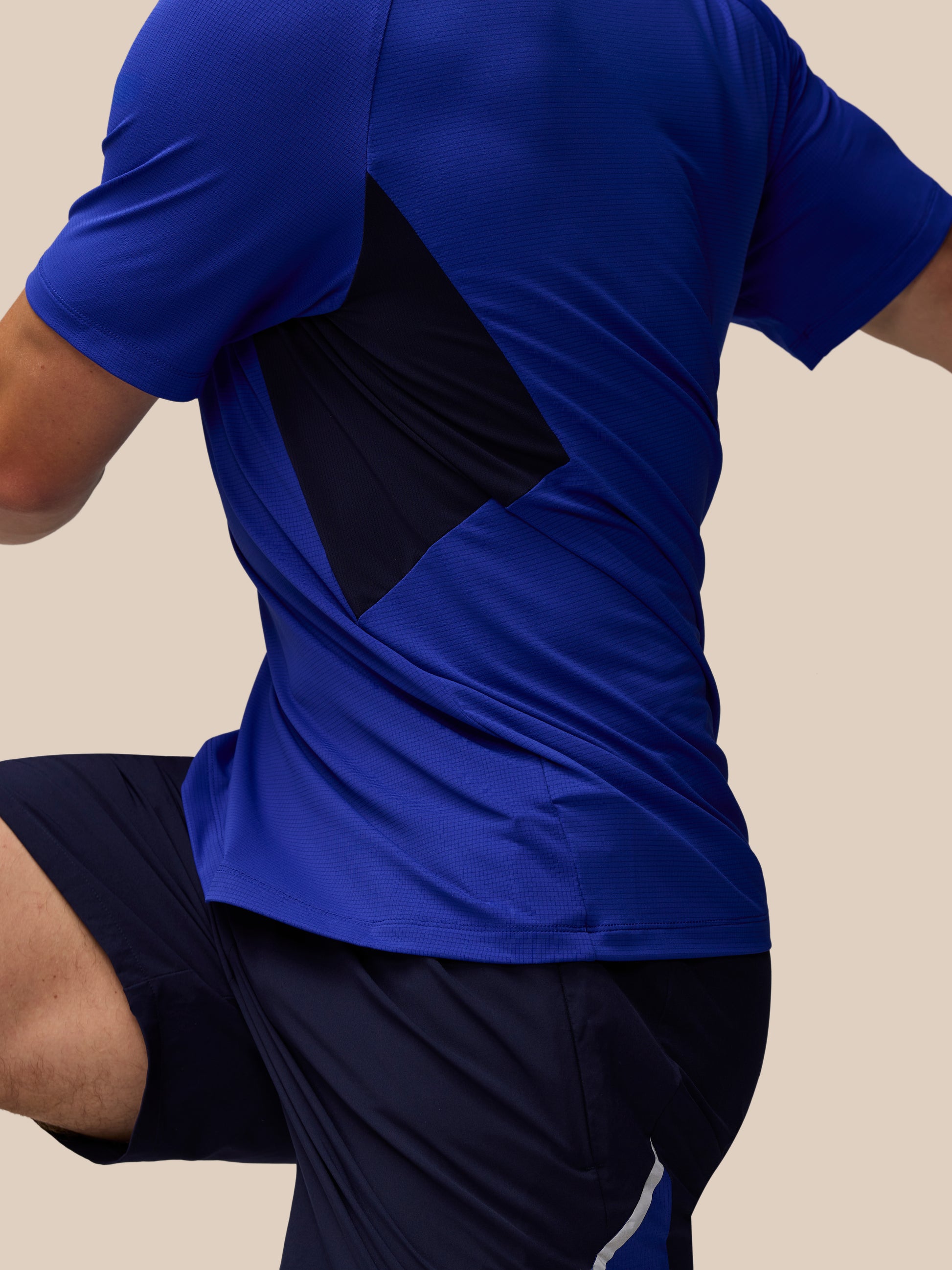 Back view of a person wearing azure blue Apex Training T Shirt with a black mesh panel