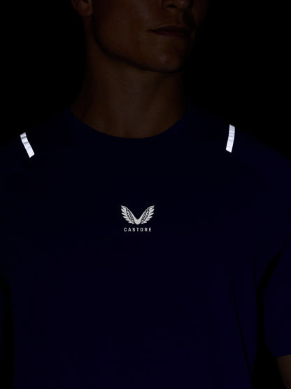 Close-up of Azure blue Apex Training T-Shirt worn by a model, featuring white reflective shoulder accents and the Castore logo on the chest.