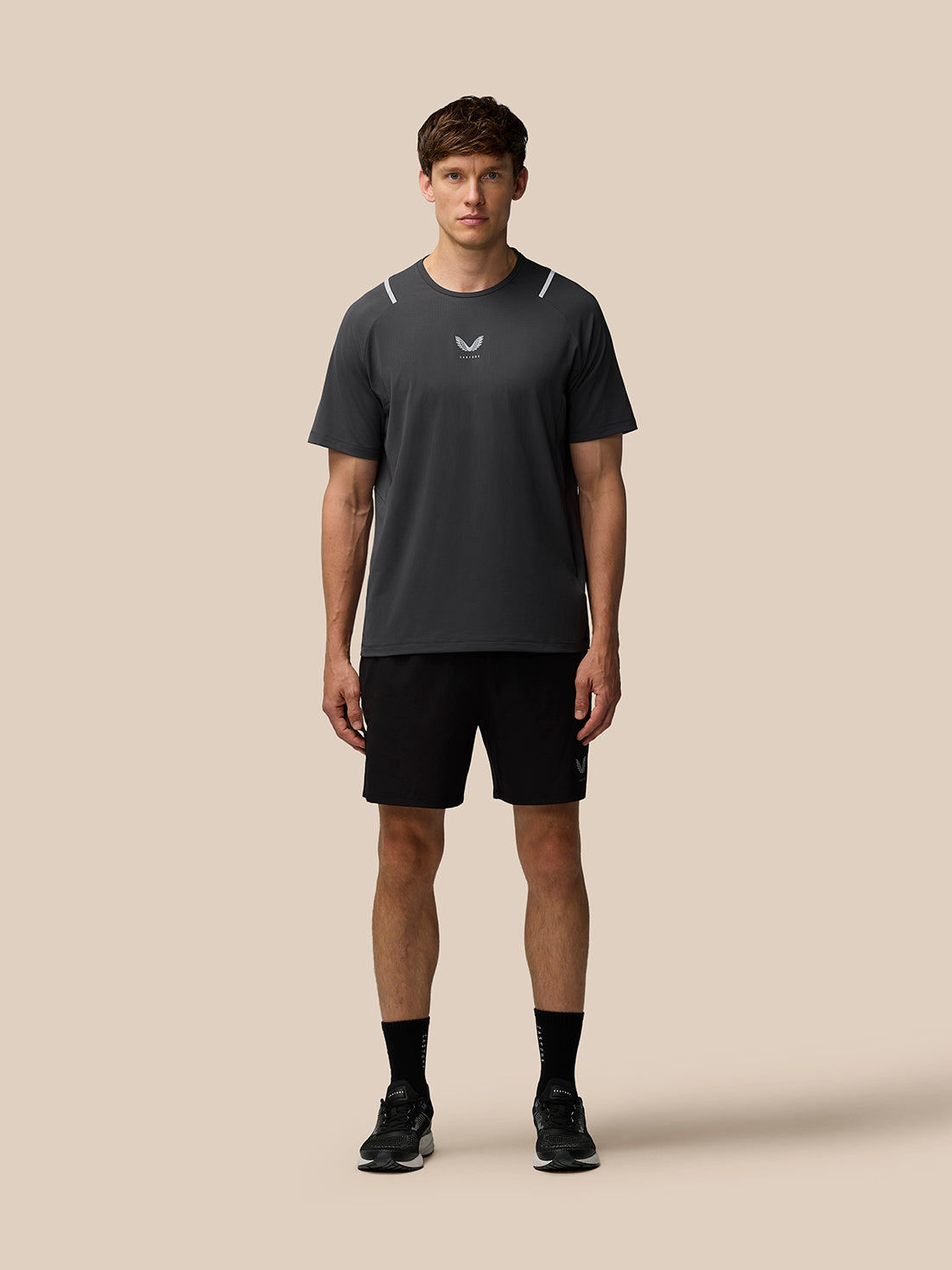 Male model wearing gunmetal Apex Training T-Shirt with reflective shoulder hits and Castore branding on chest