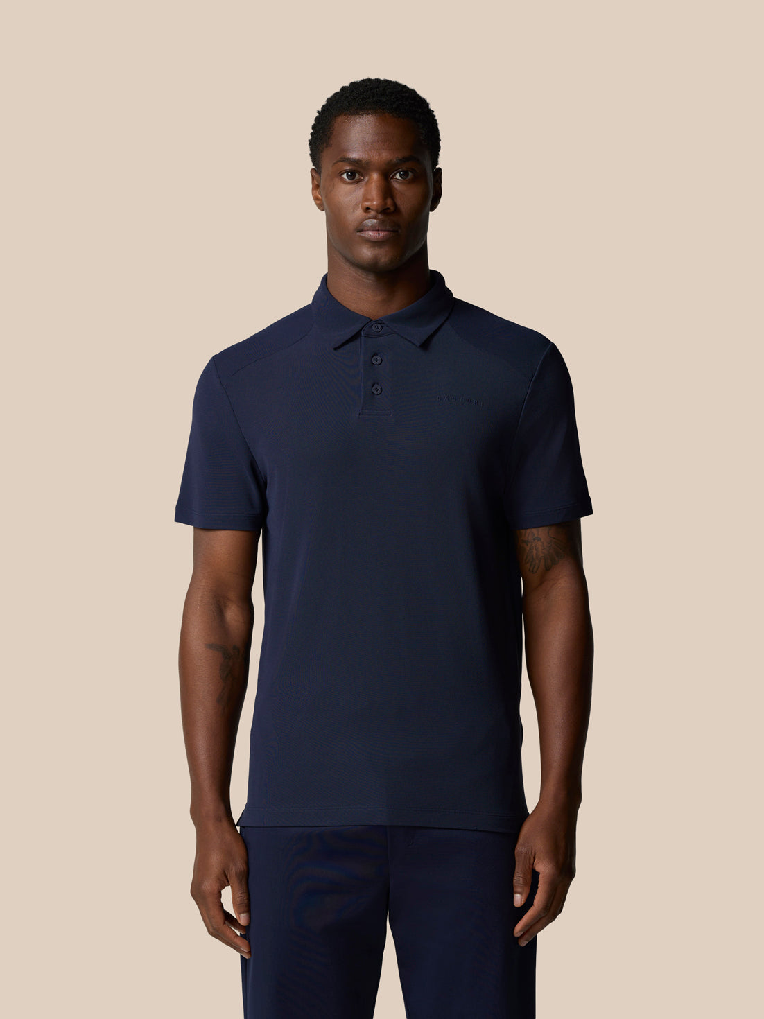 Male model wearing navy Elevated Lifestyle Polo with Castore wordmark on chest.