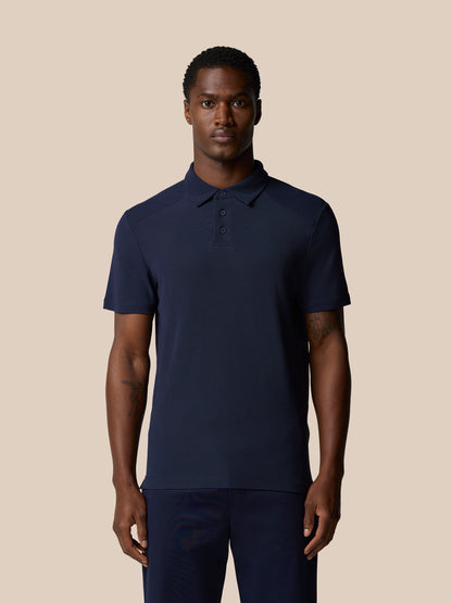 Male model wearing navy Elevated Lifestyle Polo with Castore wordmark on chest.
