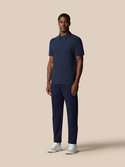 Male model in navy Elevated Lifestyle Polo with matching navy pants and white sneakers.