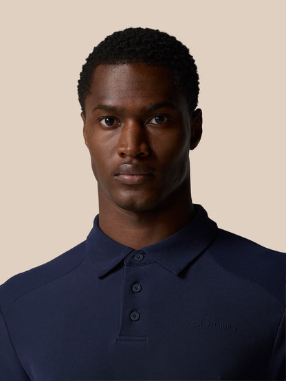 Close up of male model wearing navy Elevated Lifestyle Polo with Castore branding on chest.