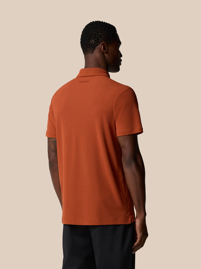 Back view of a man in a dark rust Elevated Lifestyle Polo Top showing back neck tape and branding at the upper back.