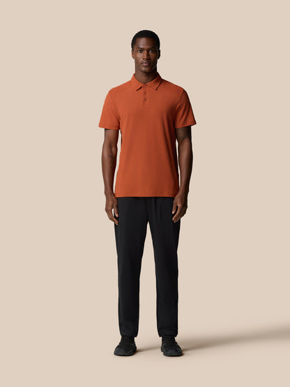 Rear view of the dark rust Elevated Lifestyle Polo Top on a male model highlighting the relaxed fit.