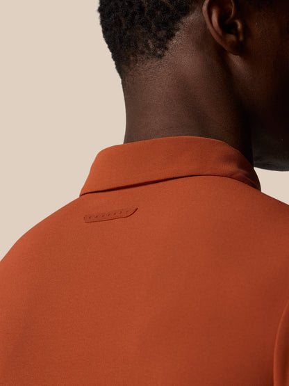 Close up of the back neck on a dark rust Elevated Lifestyle Polo Top showing the textured collar and Castore branding.