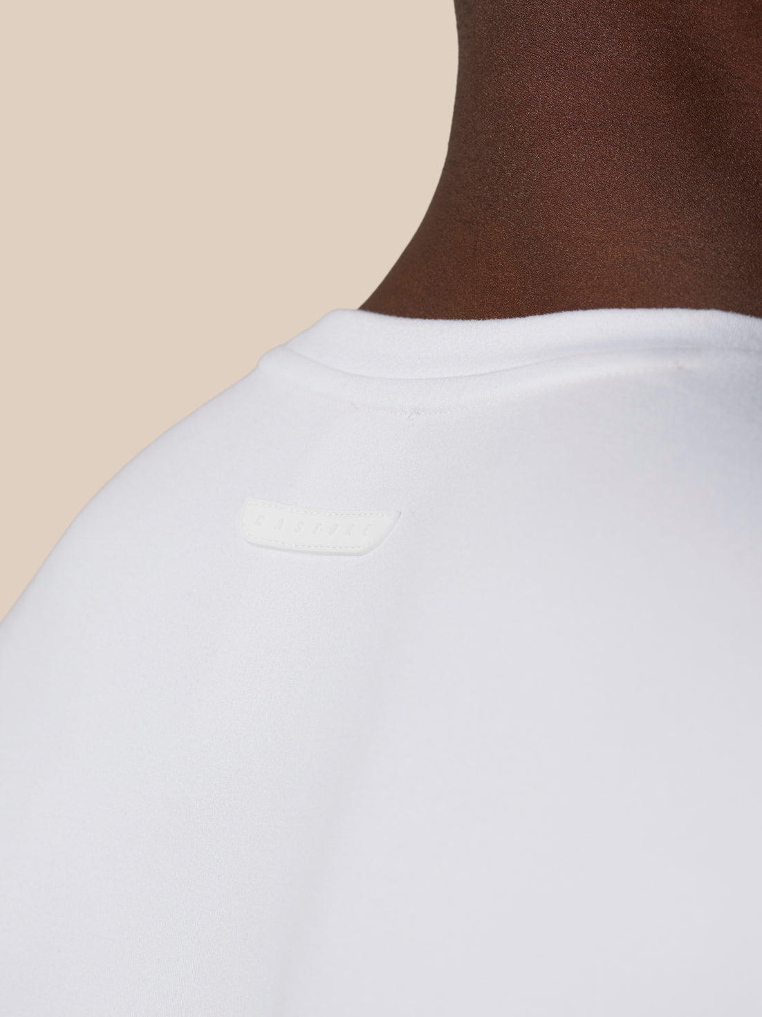 Back neck close-up of white Elevated Lifestyle T Shirt with Castore badge on the upper back