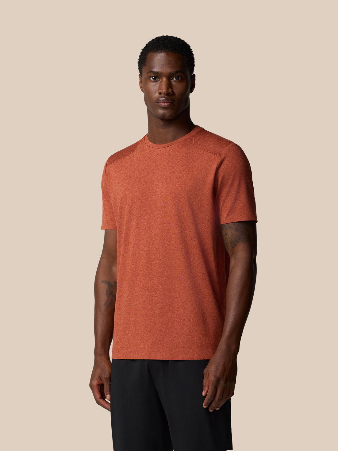 Front view of rust elevated lifestyle T shirt on a male model, featuring Castore wordmark at the left chest