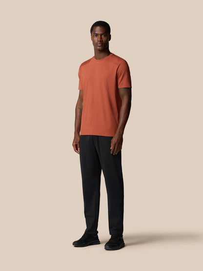 Three quarter view of rust elevated lifestyle T shirt on male model with visible left chest logo and back badge