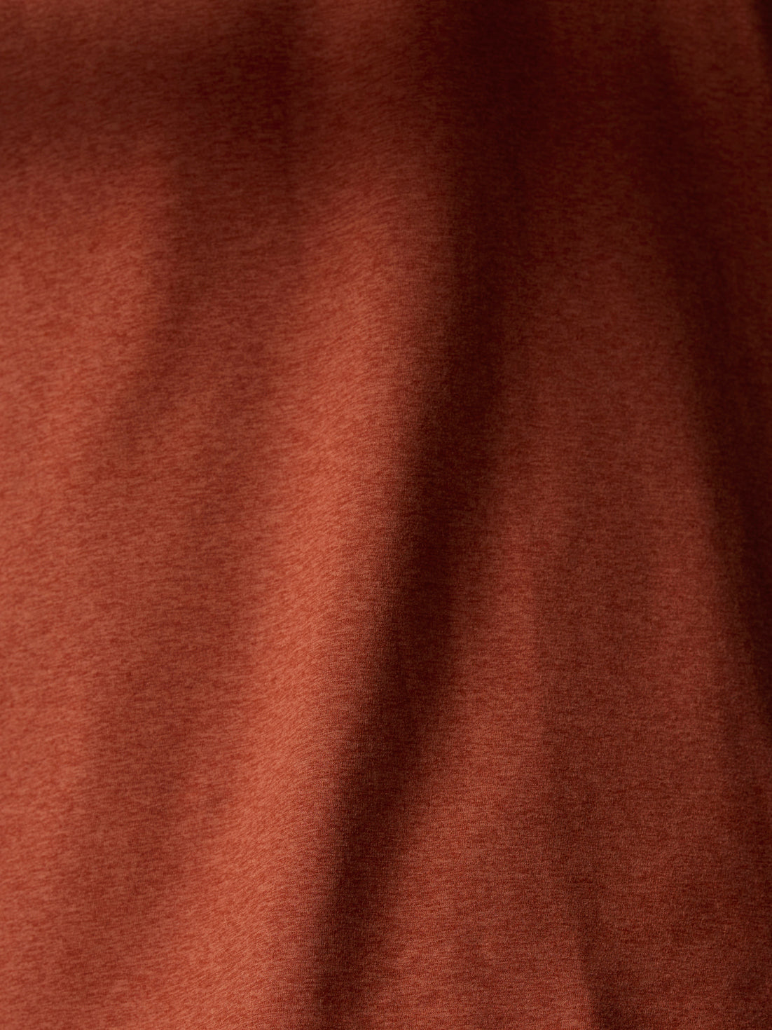 Close up of rust knit fabric around the back neck showing seam detail