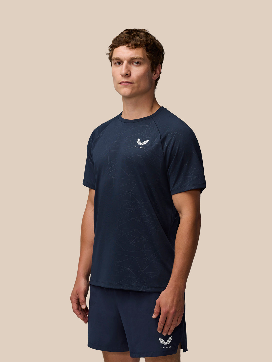 Male model wearing navy Adapt Training T-Shirt with a subtle geometric print and Castore logo on the left chest