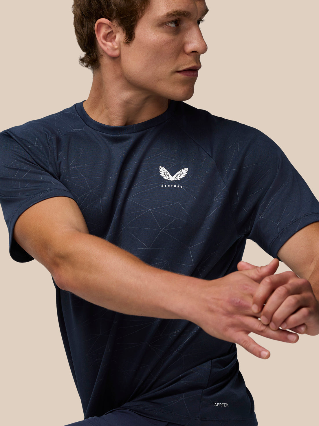 Male model wearing navy Adapt Training T Shirt with heat embossed all over geometric print and Castore logo on the left chest