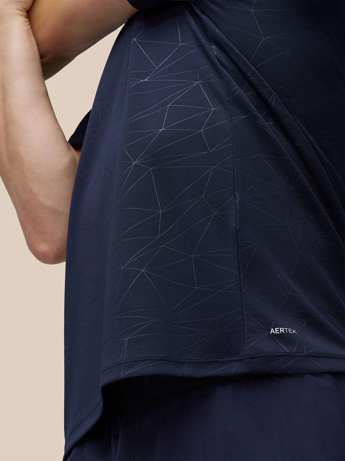 Close up of navy Adapt Training T Shirt fabric featuring a geometric line pattern and AerTek branding near the hem