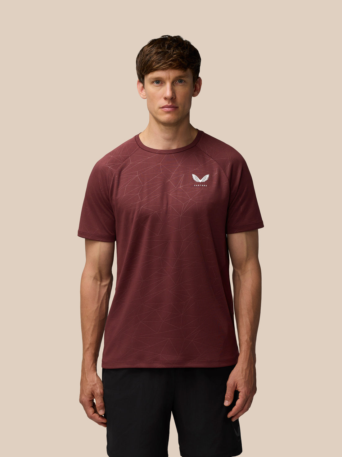 Model wearing plum Adapt Training T-Shirt with all over geometric print and Castore logo on left chest.