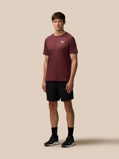 Front view of a man wearing plum Adapt Training T-Shirt with geometric print and Castore logo on the chest paired with black shorts