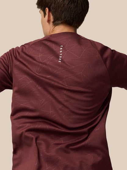 Side back view of model wearing plum Adapt Training T-Shirt with AerTek label at the hem