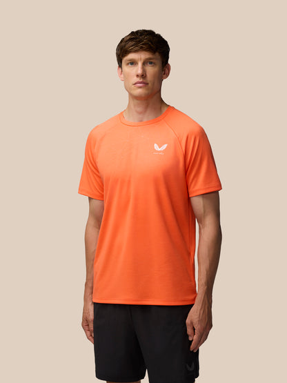 Front view portrait of a male model in an orange Adapt Training T-Shirt with the Castore logo on the chest.