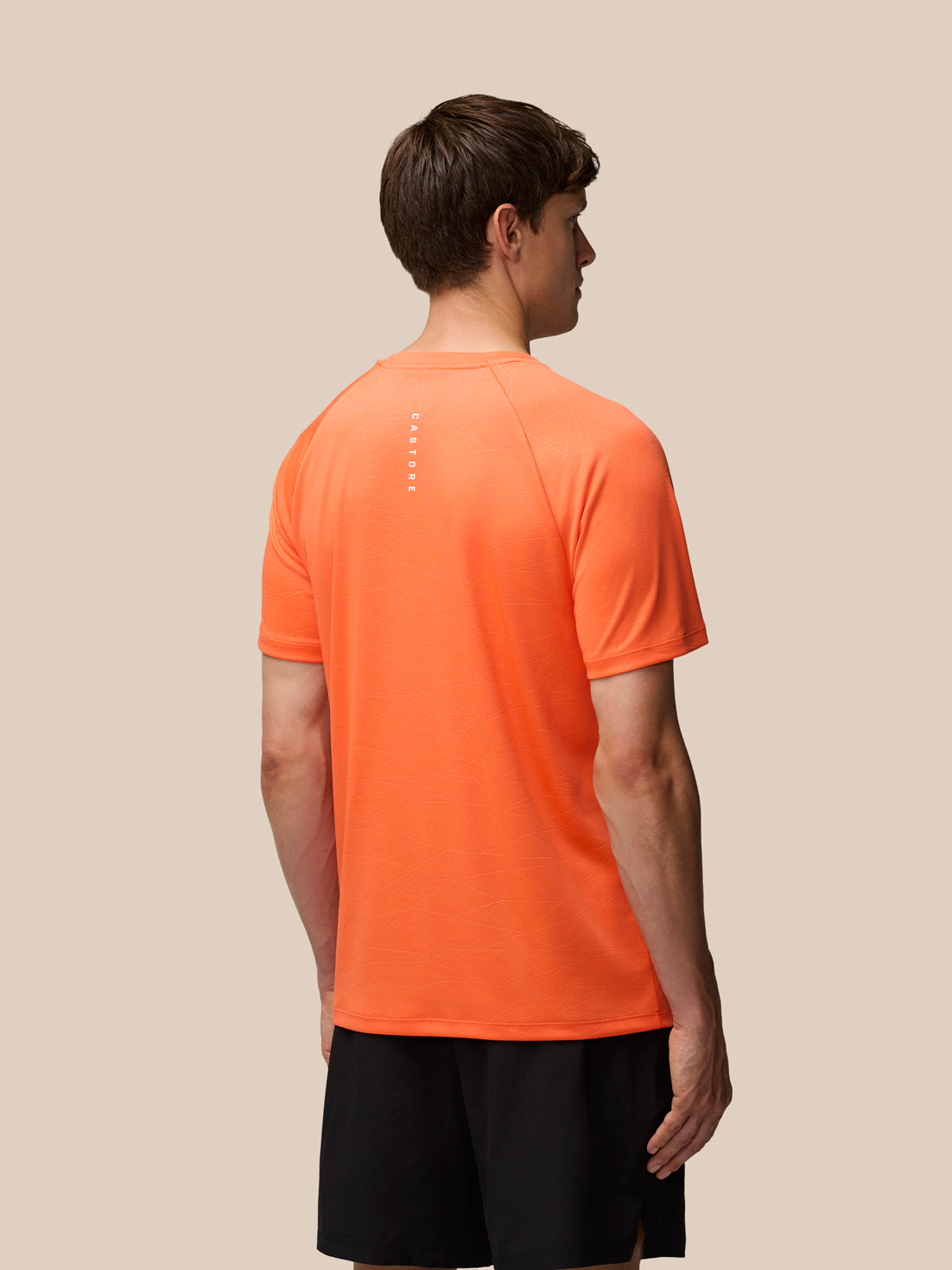 Back view of orange Adapt Training T Shirt with all over print and Castore wordmark along upper back