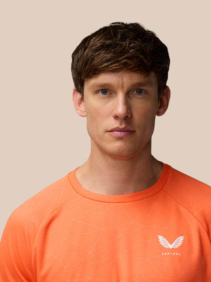 Close-up of the orange Adapt Training T-Shirt showing the faint geometric print and white Castore logo on the chest.