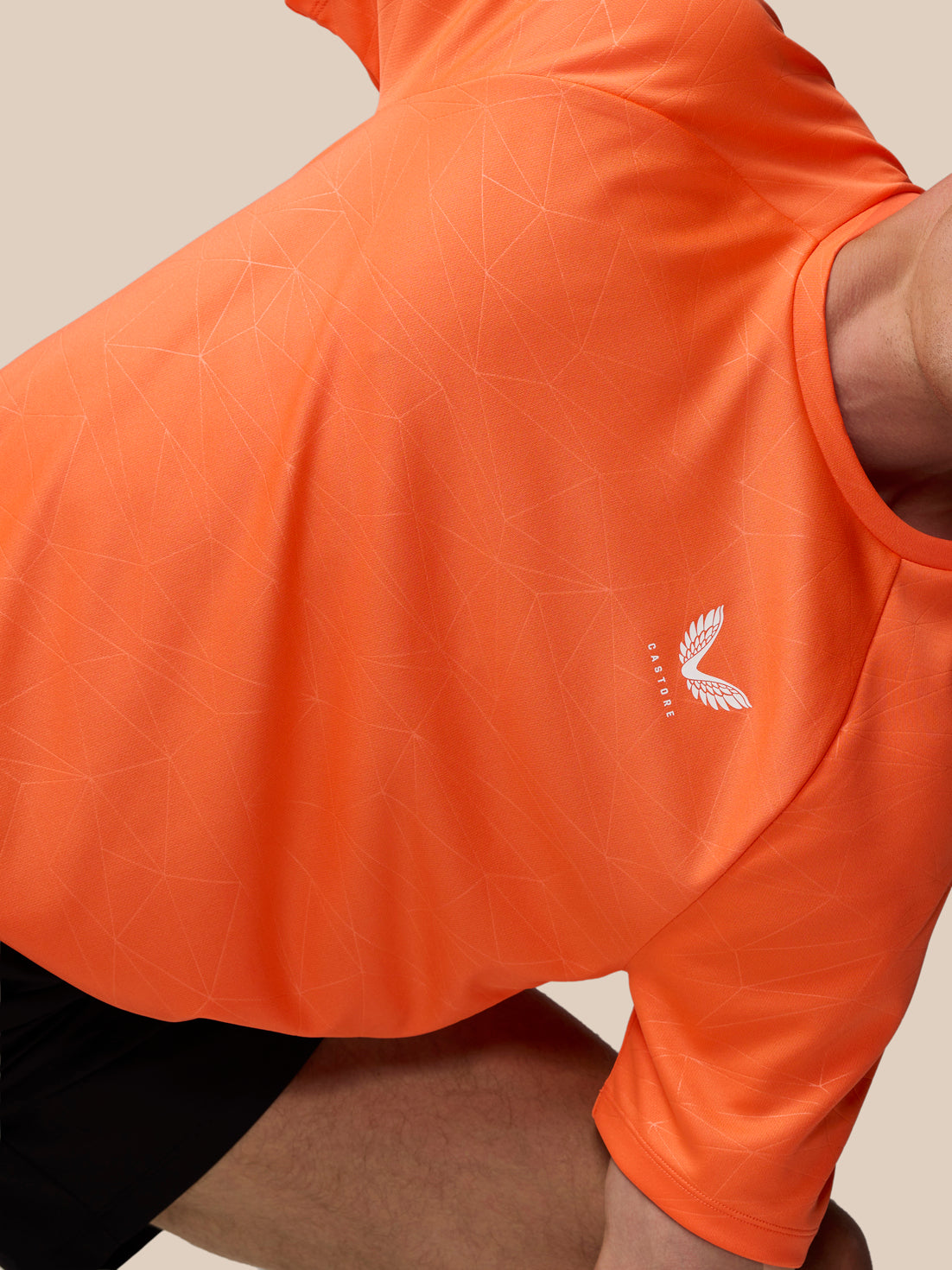 Close-up of orange Adapt Training T-Shirt with geometric print and Castore logo on the left chest.