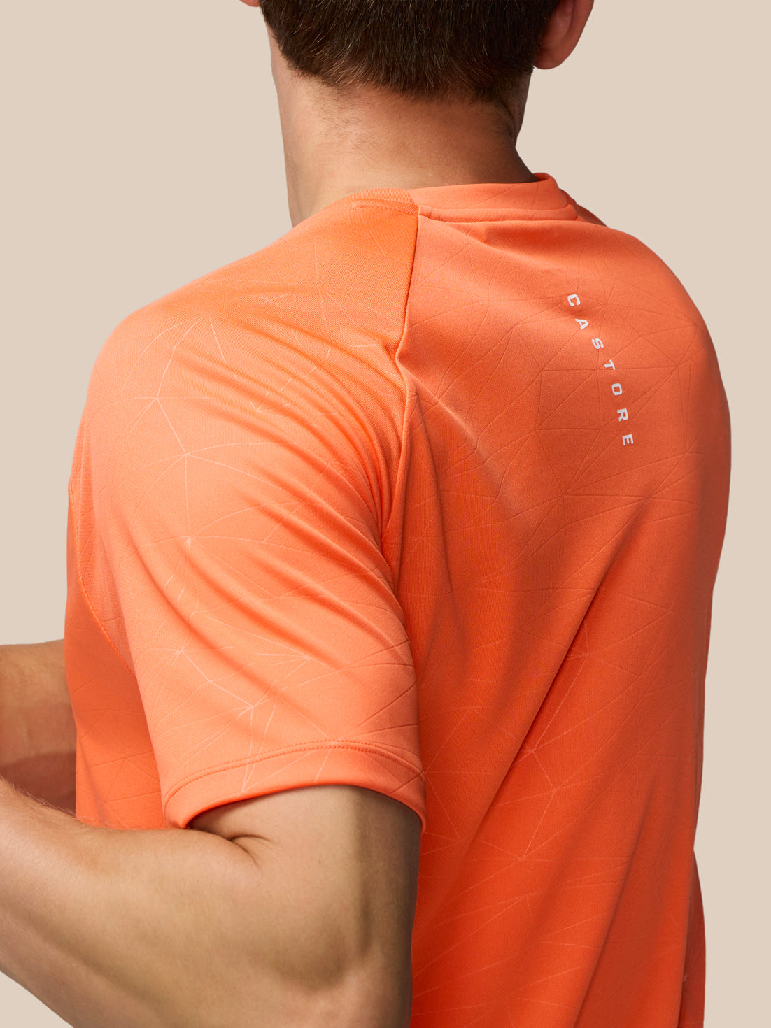 Close-up of back of orange Adapt Training T-Shirt highlighting the geometric pattern and AERTEK label near the hem.