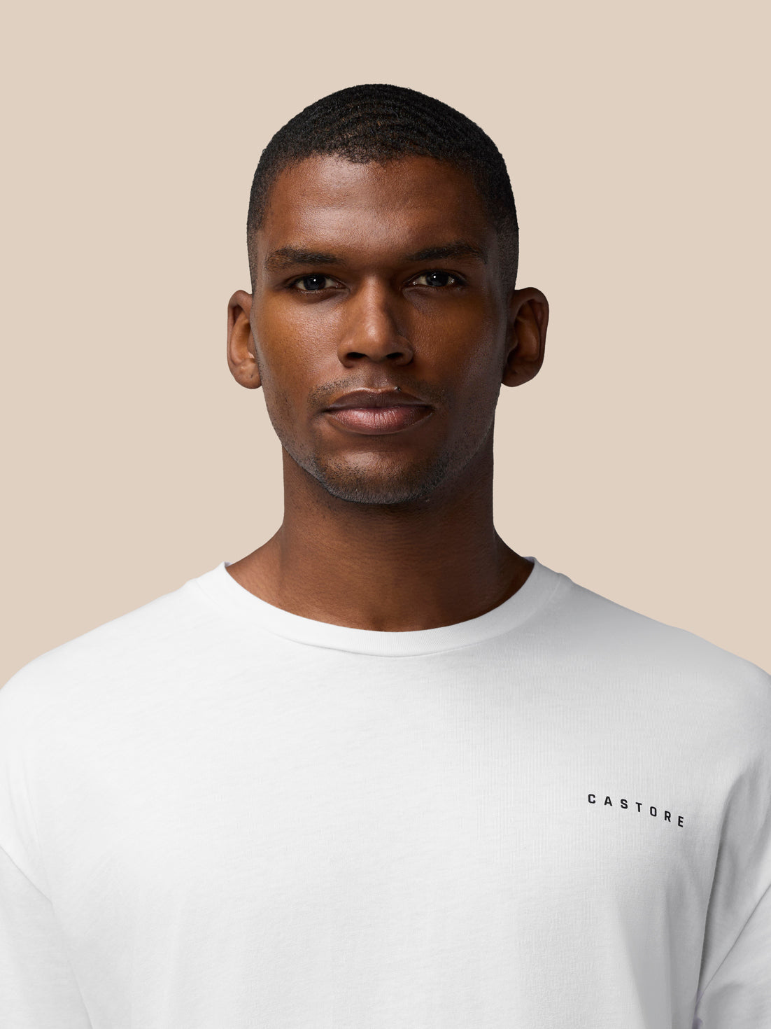 Close up of model in white T shirt with round neckline and small CASTORE logo on the chest