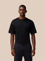 Full torso shot of a male model wearing a black Flex Cotton T Shirt with a round neckline and a small chest logo.