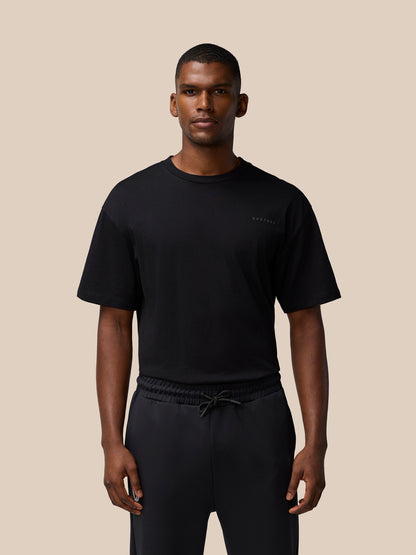 Full torso shot of a male model wearing a black Flex Cotton T Shirt with a round neckline and a small chest logo.