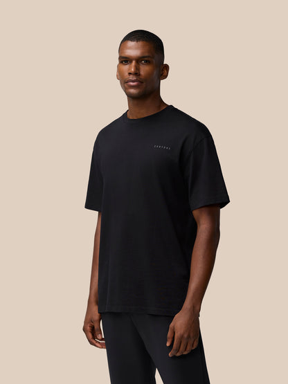 Three quarter view of a male model in a black Flex Cotton T Shirt with a subtle chest logo.