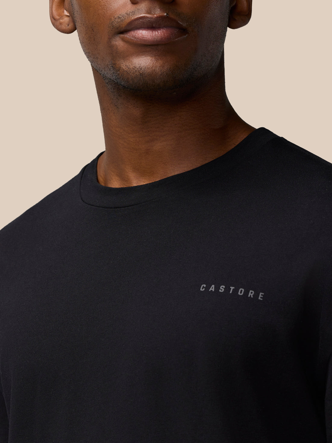 Close-up of a black Castore Flex Cotton T-Shirt worn by a model, showing round neckline and chest logo.