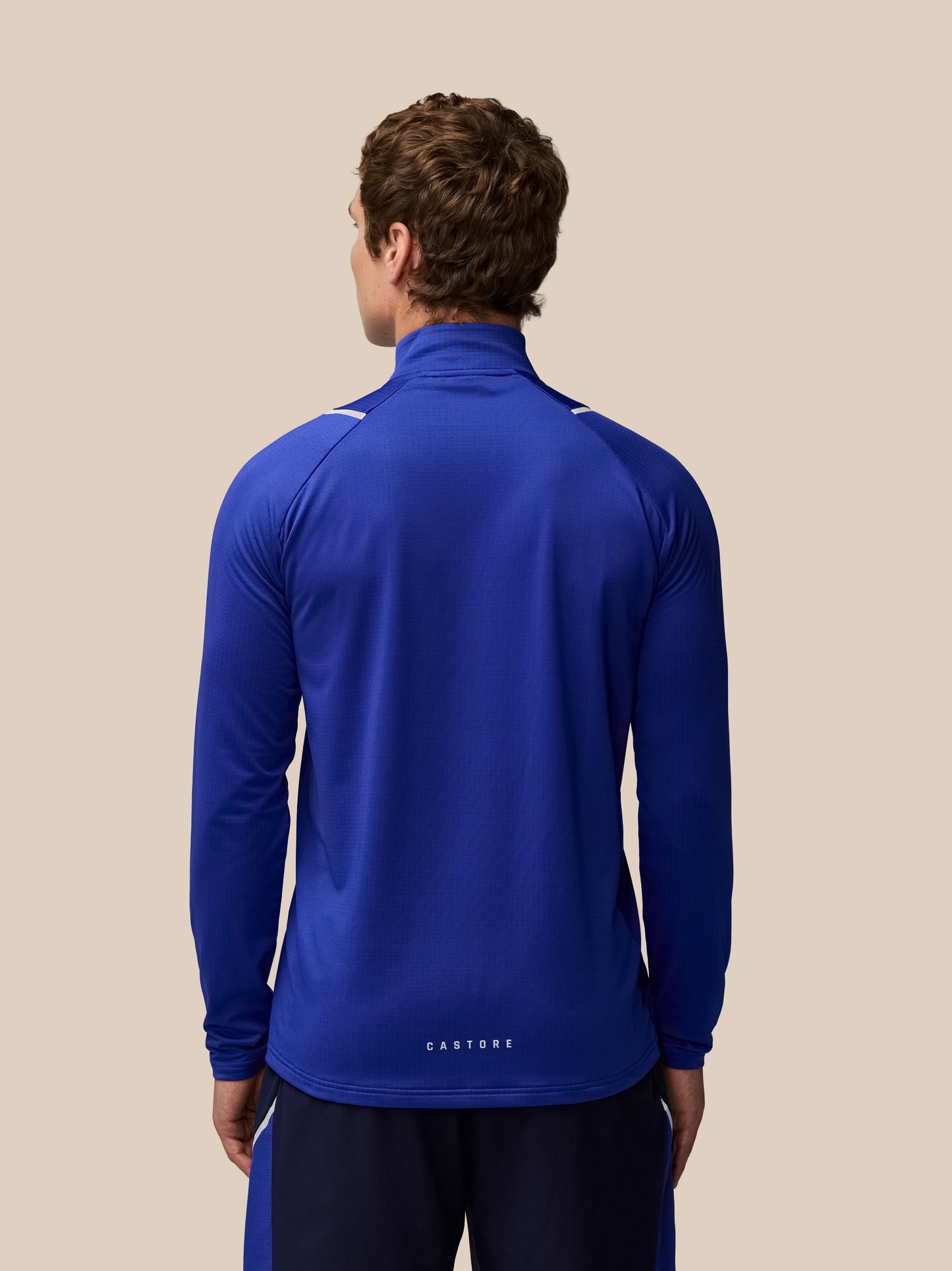 Back view of a person wearing a blue Apex Training Winterised quarter zip top with a high collar and textured fabric