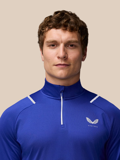 Close-up of a man wearing a blue Apex training quarter-zip top with a white zipper and Castore wing logo on the chest.