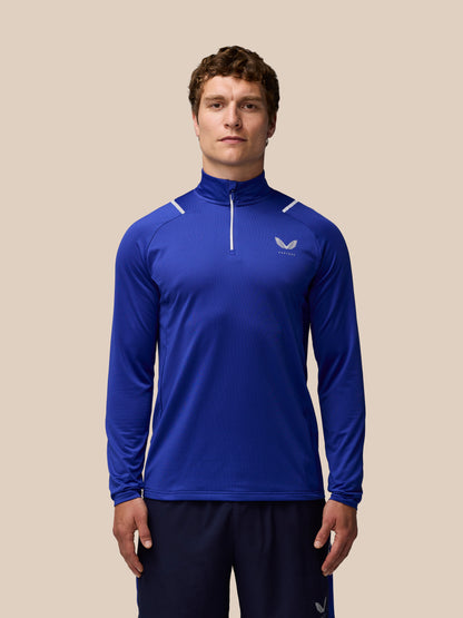 Male model wearing blue Apex Training Winterised ¼ zip top with high collar raglan sleeves and reflective detailing.