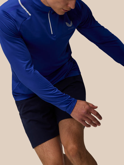 Male model wears blue Apex Training Winterised quarter zip top with a white zipper pull, reflective shoulder stripe and chest logo.
