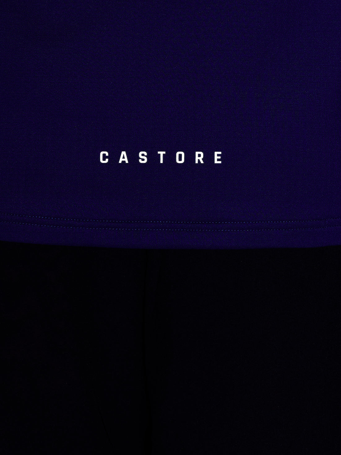 Close-up of blue athletic top fabric with Castore branding and stitched hem seam