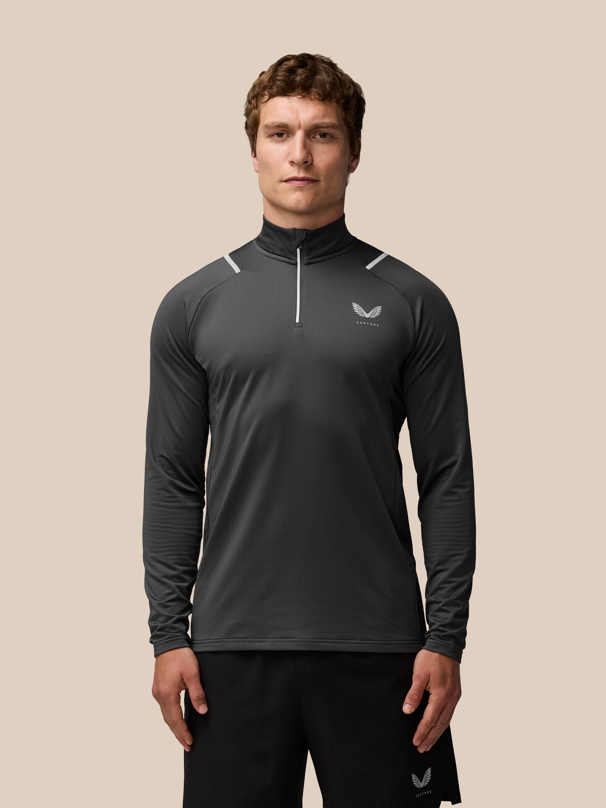 Male model wearing charcoal Apex Thermal Winterised 1/4 Zip Top with chest logo