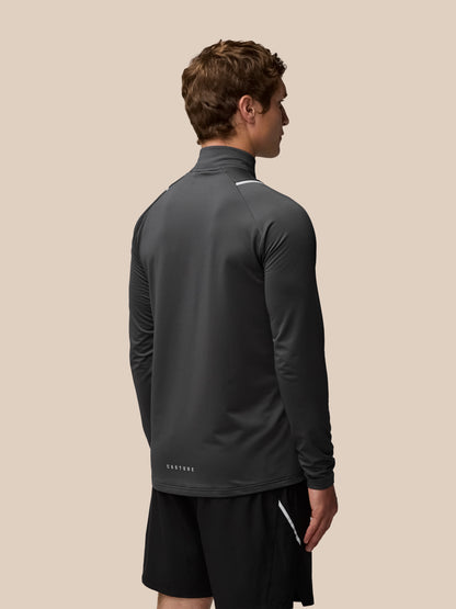 Back view of a man wearing a charcoal Apex Training Winterised quarter-zip top, featuring a high collar and subtle reflective trim across the shoulders.