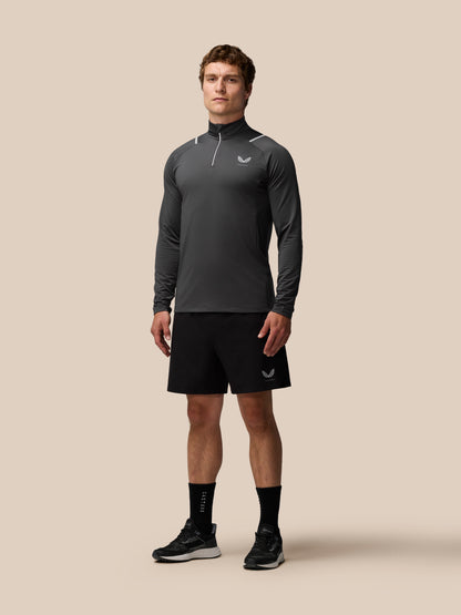 Male model wearing charcoal Apex Training Winterised quarter-zip top with high collar and subtle reflective piping.
