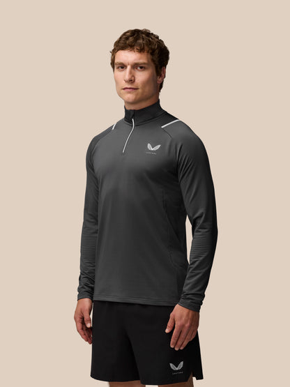 Male model wearing charcoal Apex Training Winterised quarter zip top with reflective detailing.